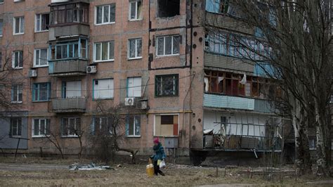 Женщина проходит мимо разрушенного жилого дома в Авдеевке, Украина ...