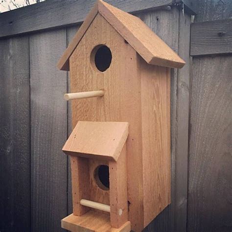 A Wooden Bird House Hanging On The Side Of A Fence