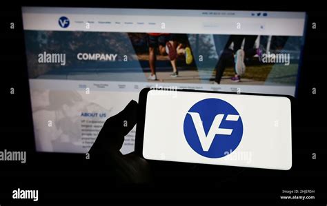 Person Holding Smartphone With Logo Of US Apparel Company VF