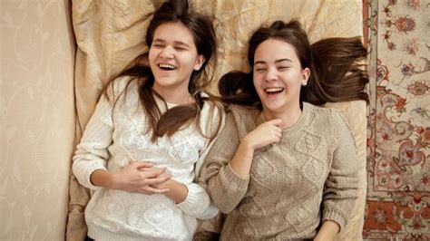 Dos chicas felices riendo relajándose en la cama y hablando amistad y