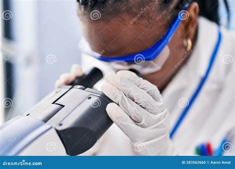 African American Woman Scientist Using Microscope At Laboratory Stock