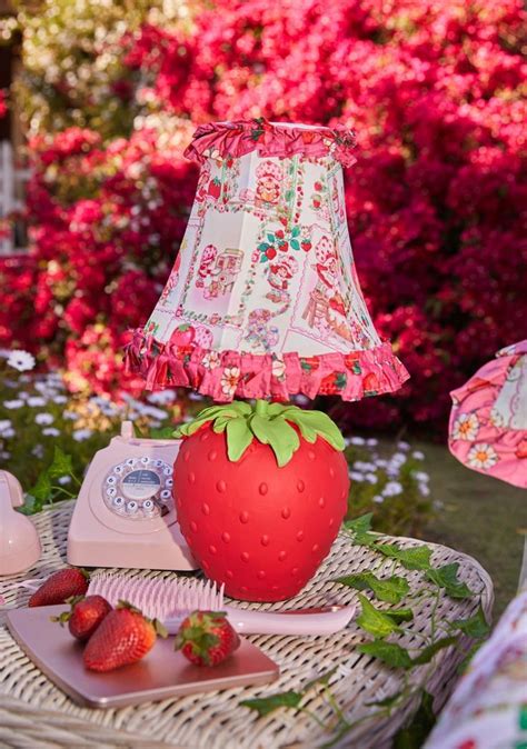 A Strawberry Lamp Sitting On Top Of A Wicker Table Next To A Plate Of