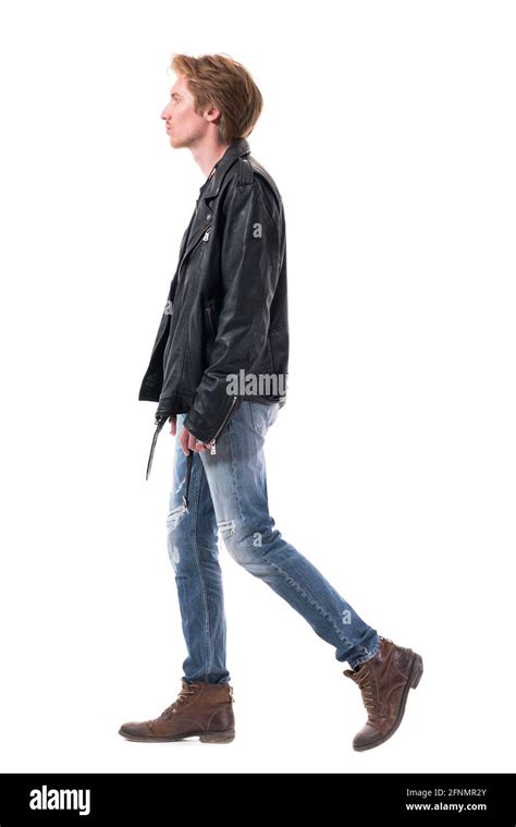 Side view of walking young man in leather jacket and jeans with boots. Full body length isolated ...