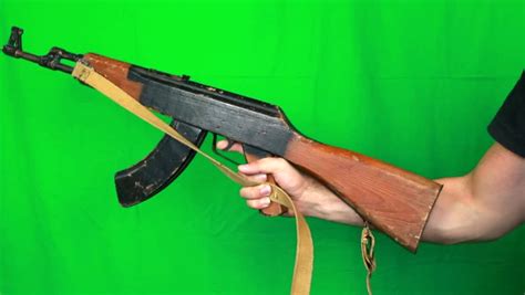 Pulling Out A Ak 47 Assault Rifle From Left Side Of A Screen Holding