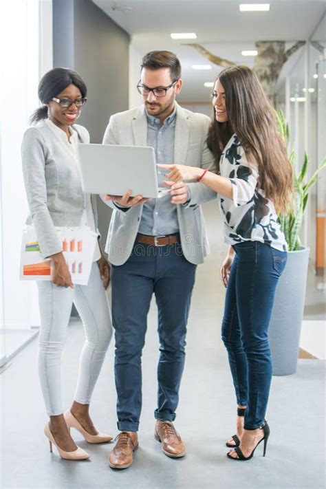 Group Of Three Business People With Laptop Having Informal Meeting In