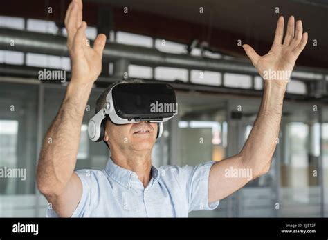 Mature Businessman Wearing Virtual Reality Simulator Gesturing In