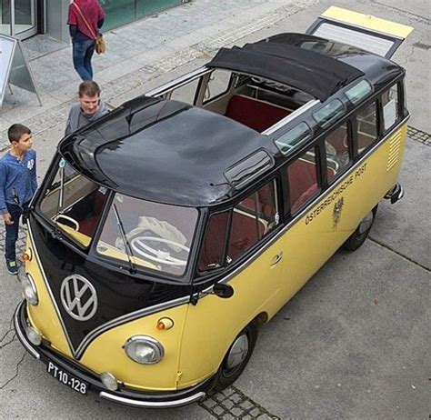 An Old Vw Bus Is Parked On The Side Of The Road With Two People