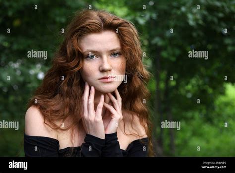 Portrait Of Pretty Ginger Girl With Long Red Hair And Freckles Standing In Summer Park Young