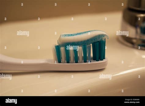 A Toothbrush Resting On A Sink With A Swirl Of Toothpaste Of Top Of The