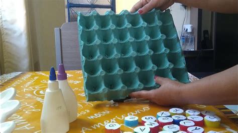 Two Hands Holding An Egg Tray Over A Table With Cupcakes On It