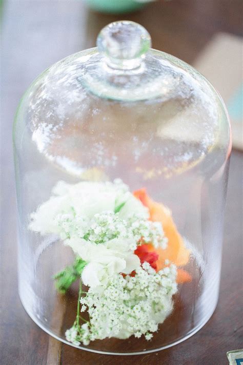 A Glass Clochet With Flowers In It On A Wooden Table Next To Other Items