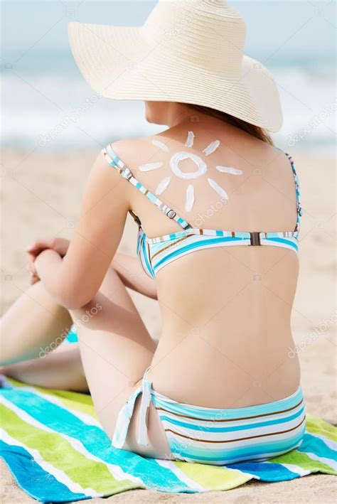 Bikini Woman In Sunhat With Sun Drawn On Back At Beach Stock Photo