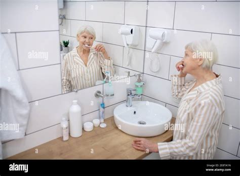 Elderly Woman Brushing Her Teeth In The Bathroom Stock Photo Alamy