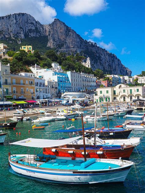 Many Boats Are Docked In The Water Near Some Buildings And Cliffs On A