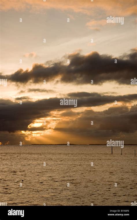 sunset with bright sun rays over ocean Stock Photo - Alamy