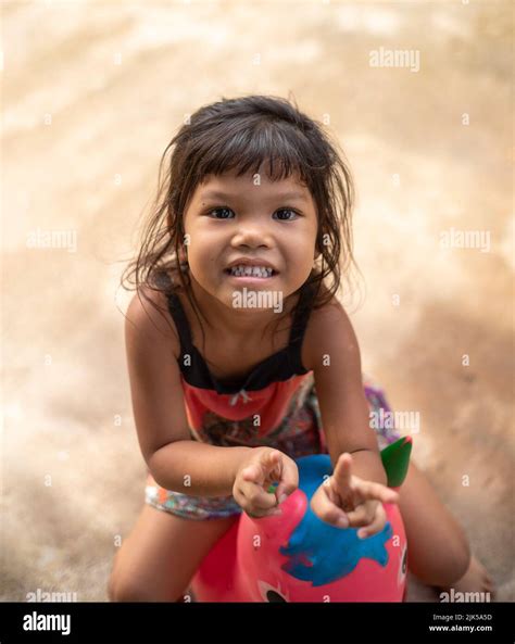 Une Jeune Fille Thaïlandaise Sourit à La Caméra Tout En étant Assise Sur Un Jouet De Trémie D