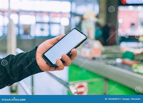 The Guy Is Holding A Smartphone With A White Screen In The Store Stock