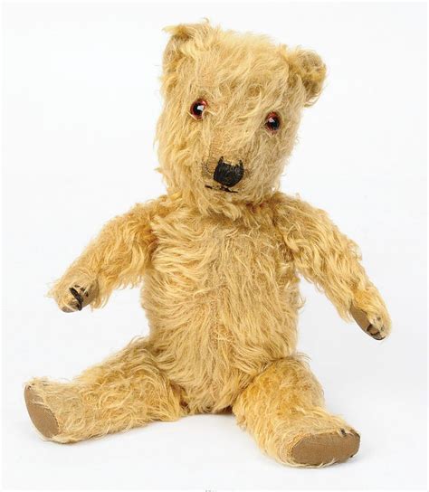 A Brown Teddy Bear Sitting Up Against A White Background