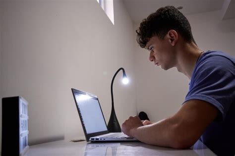 Um Macho Trabalhando No Laptop Uma L Mpada E Uma Mesa Foto Premium