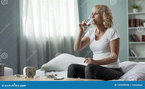 Blond Mature Female Sitting Bed And Taking Pills Health And Medicine