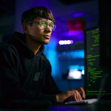 Low Key Lighting Shot Of Male Computer Hacker Sitting In Front Of