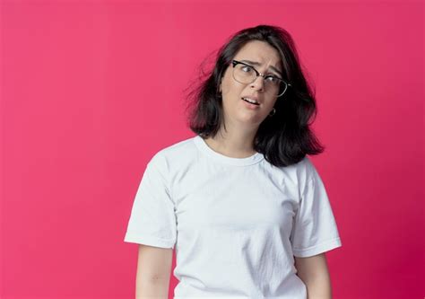 Impresionada joven bastante caucásica con gafas mirando al lado aislado