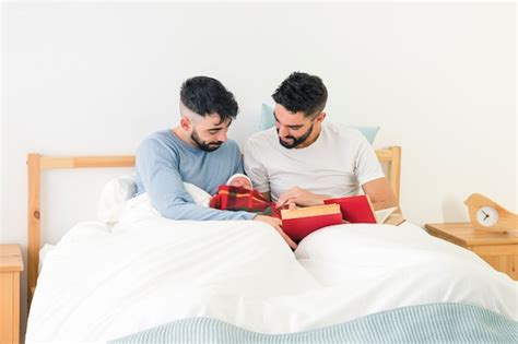 Beau Jeune Couple Gay Avec Des Livres à La Main à La Recherche De Leur Bébé Enveloppé Dans Une
