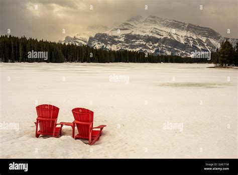 The Iconic Red Chairs In The Snow In Front Of The Two Jack Lake In