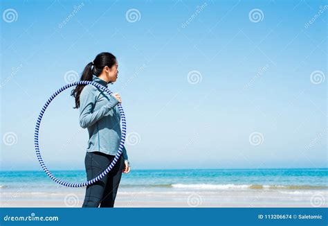 Muchacha Que Ejercita Con El Aro Del Hula En La Playa Foto De Archivo