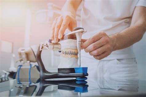 Premium Photo Dental Technician Working With Articulator In Dental Lab