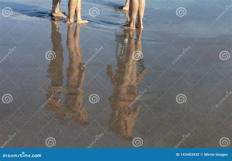 Young Bathers In Bathing Suits Reflection On Freshly Wet Sand Stock