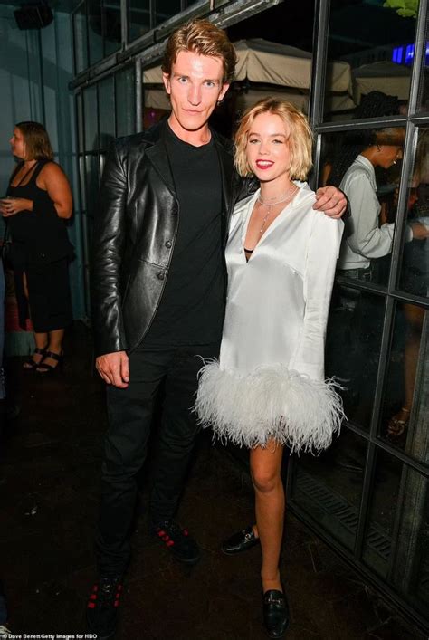 A Man And Woman Standing Next To Each Other In Front Of A Glass Wall At