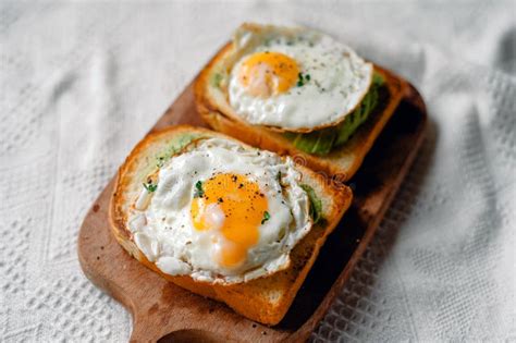 Tostadas Con Huevos Fritos Y Aguacate En Una Tabla De Corte De Madera
