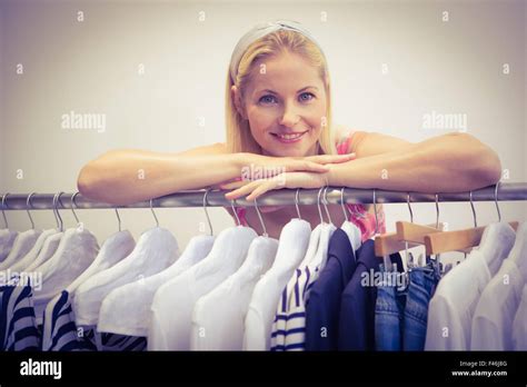 Pretty Blonde Smiling At Camera By Clothes Rail Stock Photo Alamy
