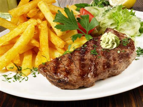 Bife De Carne Grelhada Batatas Fritas E Manteiga De Erva Foto De