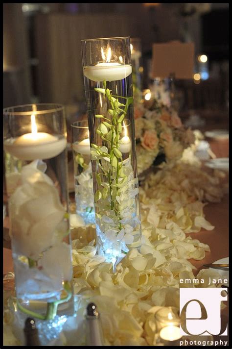 flowers and candles are arranged in glass vases on a long table with ...