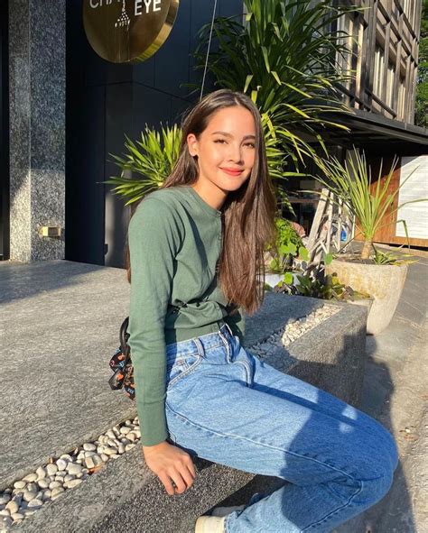 A Woman Sitting On The Ground In Front Of A Building Wearing Jeans And