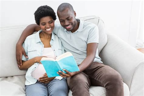 Pareja Embarazada Leyendo Un Libro En Casa Foto Premium