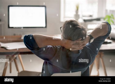 Back View Of Relaxed Businessman With His Hands Behind Head Sitting By