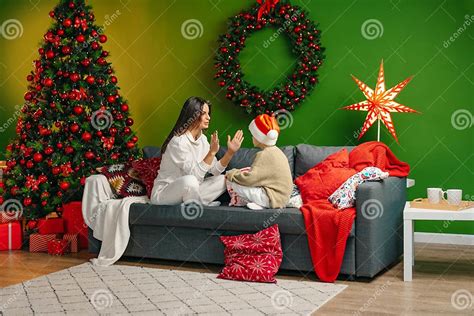 Mother Sitting On A Sofa With Her Son In Living Room Decorated For