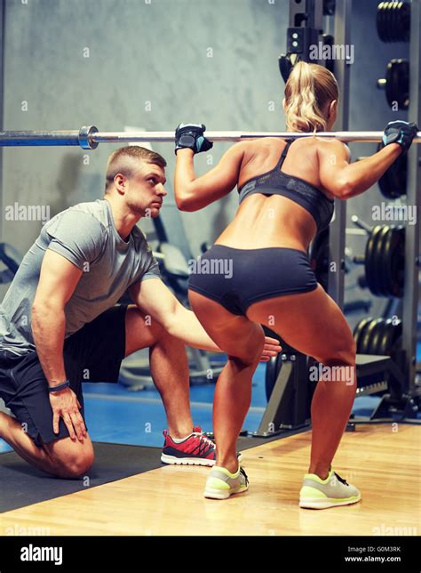 El hombre y la mujer con el barbell flexión músculos de gimnasio