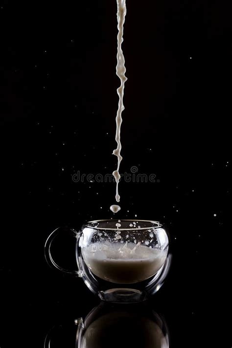 Pouring Process Of Milk Into A Glass Cup With Reflection Under Glass Cup Splashes And Drops