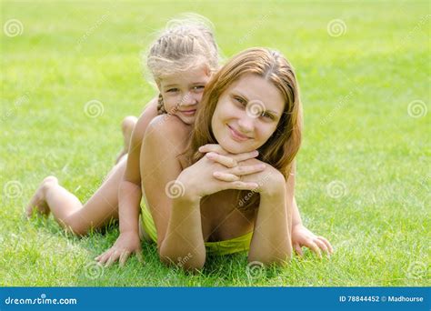 Mum And Daughter Lie On Green Lawn In A Bikini And Look In The Frame Stock Photo Image Of