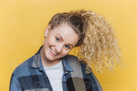 Funny Cute Female Model With Curly Blonde Pony Tail Has Positive Smile Has Fun Alone Indoor