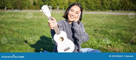 Beautiful Asian Girl With Happy Smile Shows Her Ukulele Sits Outside