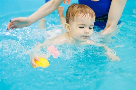 Um Menino De 2 Anos Aprende A Nadar Em Uma Piscina Um Treinador