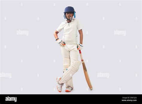 Full Length Of A Boy In Cricket Uniform Standing With Bat Stock Photo