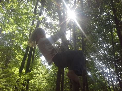 A Girl Is Swinging On A Rope In The Woods While Sun Shines Through The