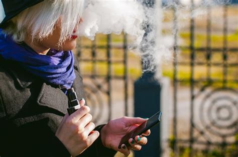 Premium Photo Young Woman Using Mobile Phone While Smoking At Park