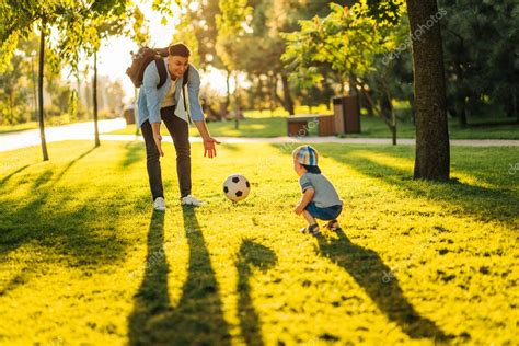 padre con un hijo pequeño juega al fútbol en la hierba verde en el